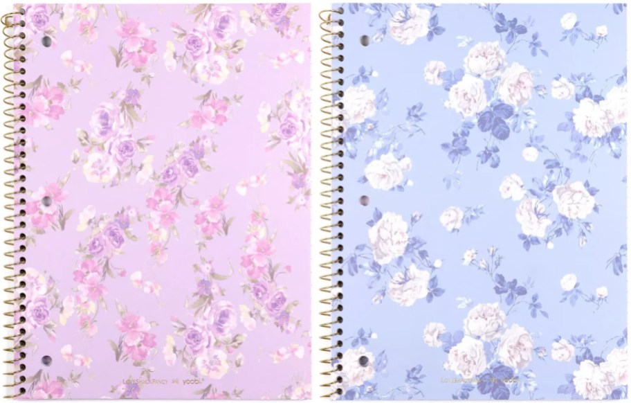 Two floral spiral notebooks side-by-side: a light pink notebook with pink flowers and a light blue notebook with white flowers.