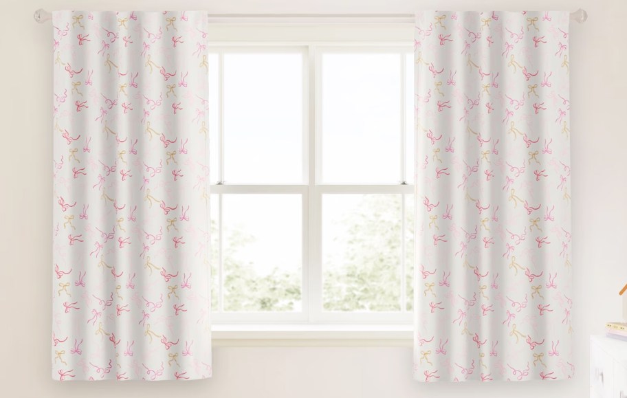 white and pink bow print curtains over a window