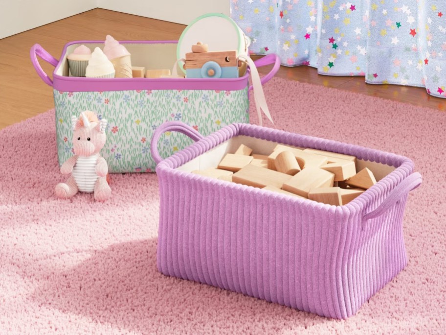 two storage baskets filled with toys on a pink rug