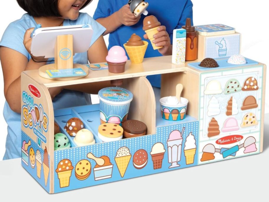 two kids playing with a melissa & doug Ice Cream counter playset