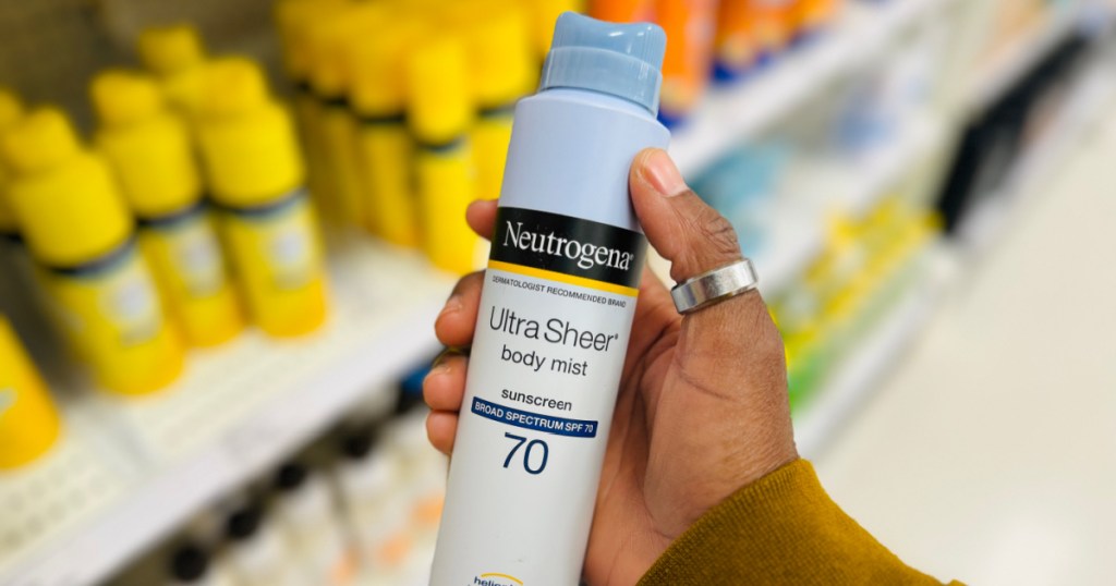 Hand holding bottle of Neutrogena sunscreen