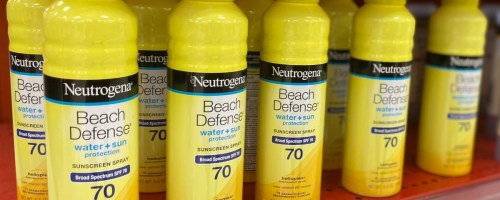 cans of Neutrogena Beach Defense Spray Sunscreen on a store shelf
