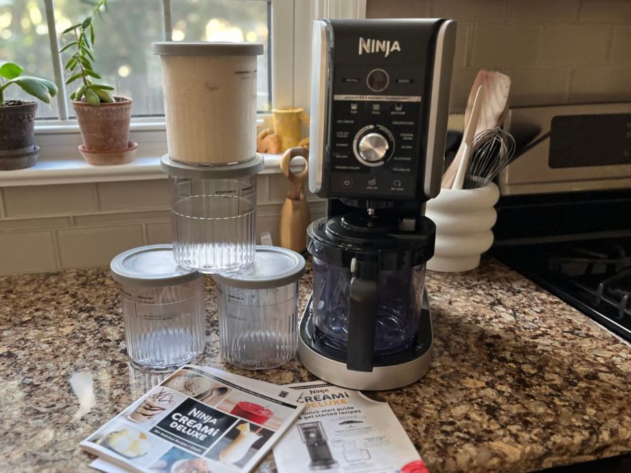 Ninja Creami Deluxe Ice Cream Maker w/ Extra Pints on a Counter