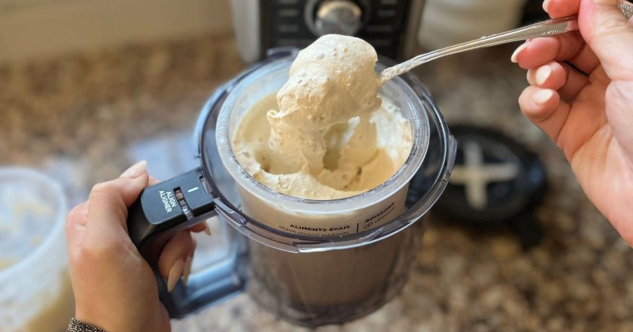 Hand scooping a spoonful of ice cream out of a ninja creami pint