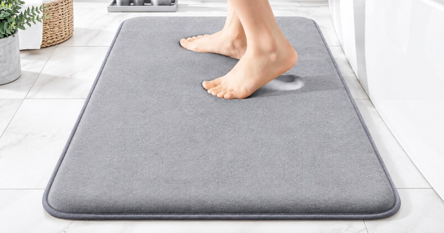 woman stepping on a grey bath mat in bathroom