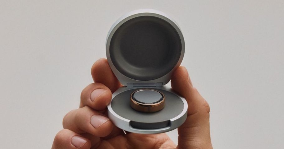 Hand holding a round ring box with an Oura Ring 5
