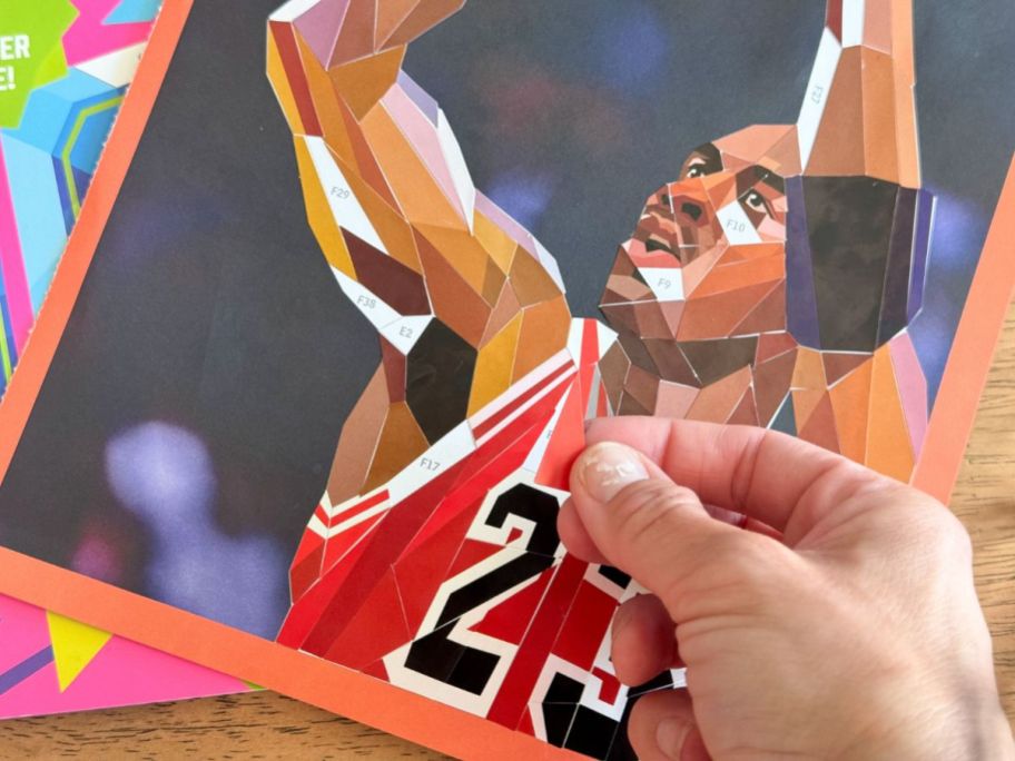 hand putting sticker on michael jordan page from Paint By Sticker '90s Edition Book