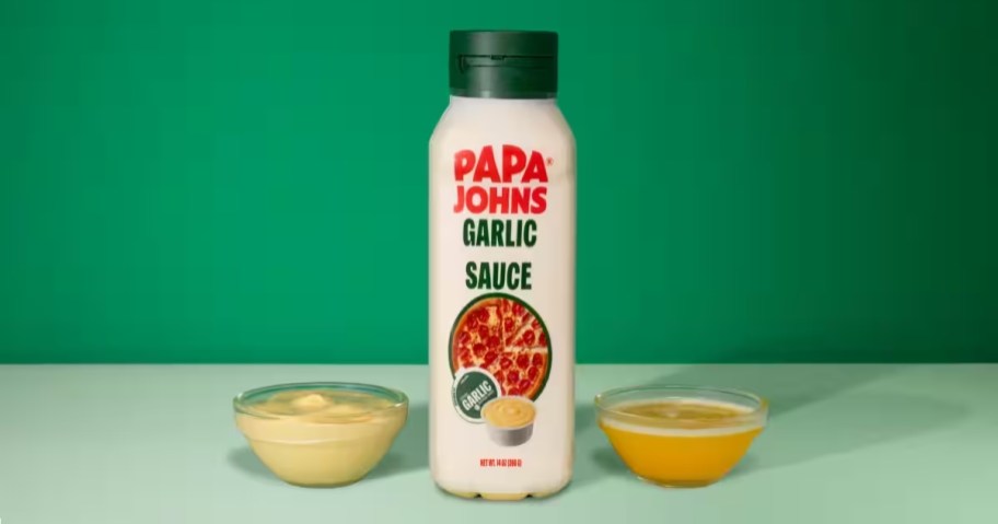 bottle of papa johns garlic flavored sauce with cups on sauce next to it