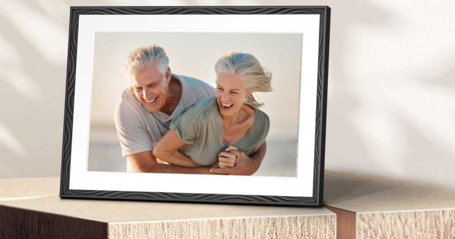 A framed photo of a happy older couple embracing and laughing, set on a wooden surface.
