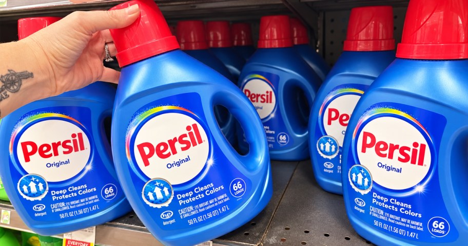 hand grabbing a blue bottle of Persil Laundry Detergent from store shelf