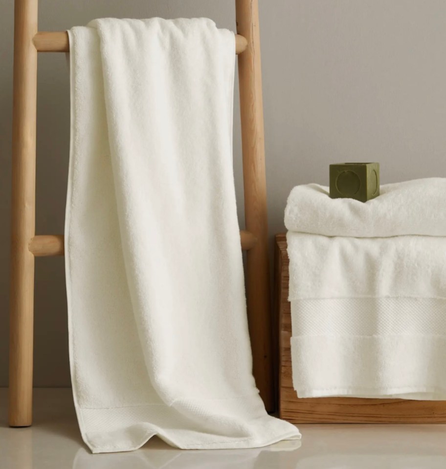 White bath towel hanging on wooden ladder and bathroom