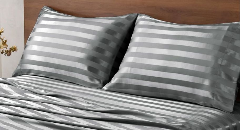 a bed with satin sheets and pillowcases on it