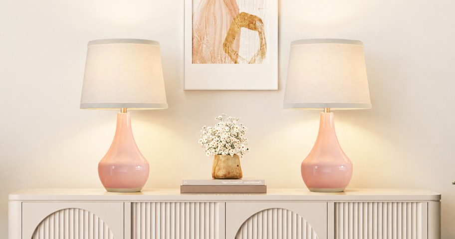two pink table lamps on a white sideboard