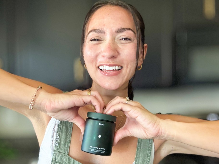 woman holding up a green jar of probiotics
