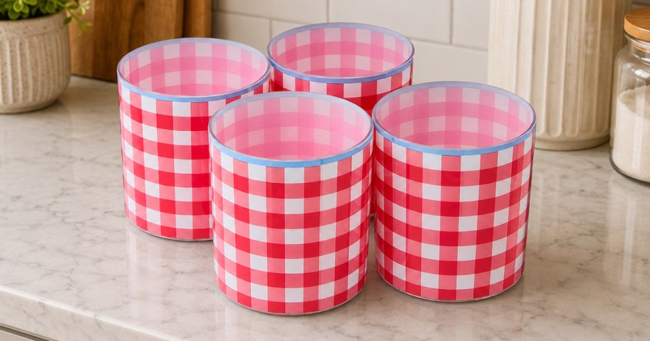 Four lowball tumblers with a red and white checkered pattern, arranged on a marble surface.