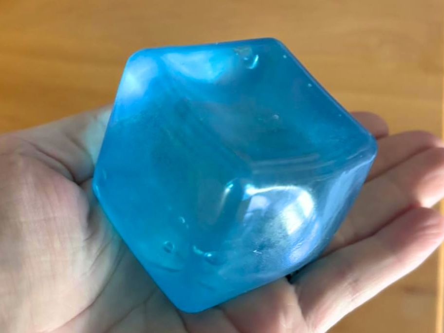 Hand holding a blue squishy cube sensory toy