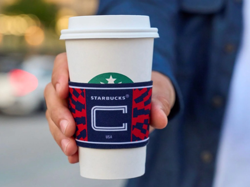 Hand holding a Starbucks cup with soccer sleeve
