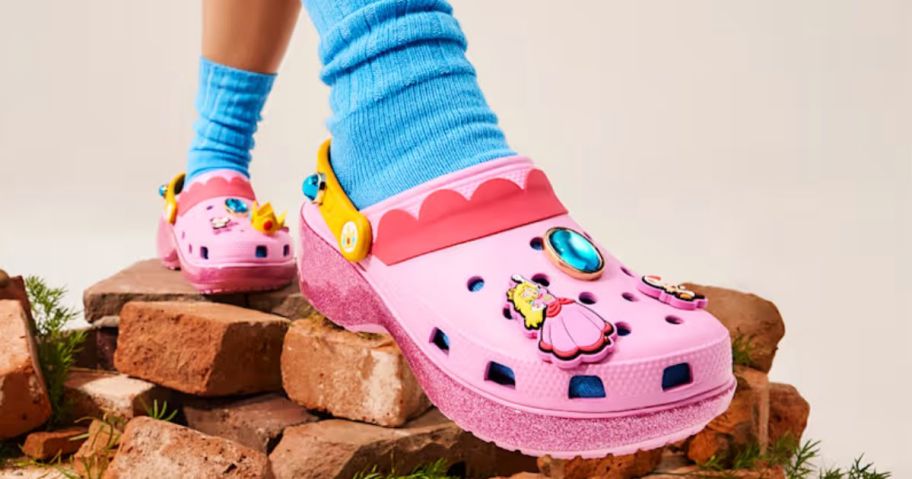 Feet wearing Princess Peach Crocs Clogs