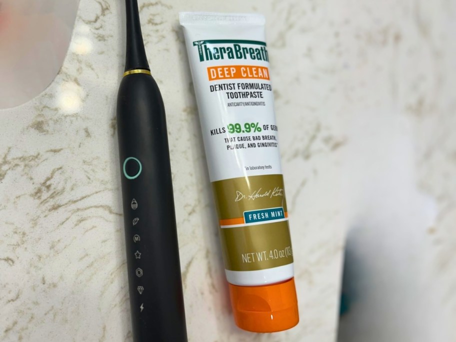 tube of therabreath toothpaste and electric toothbrush on bathroom counter