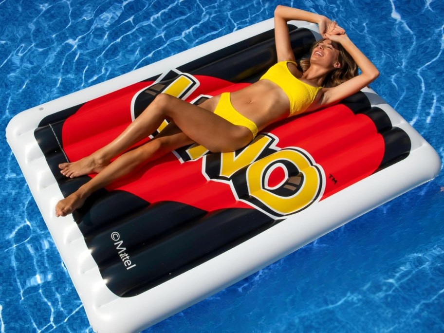 woman laying on a large UNO card pool float