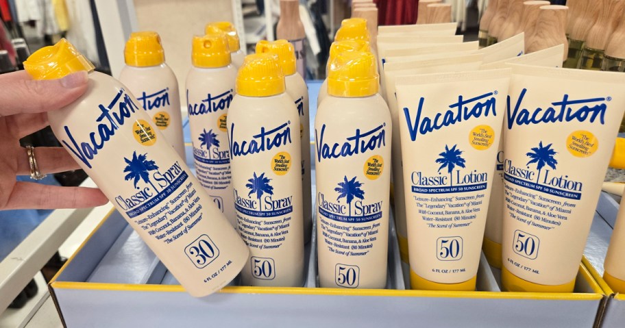 hand grabbing bottle of Vacation Sunscreen from store display