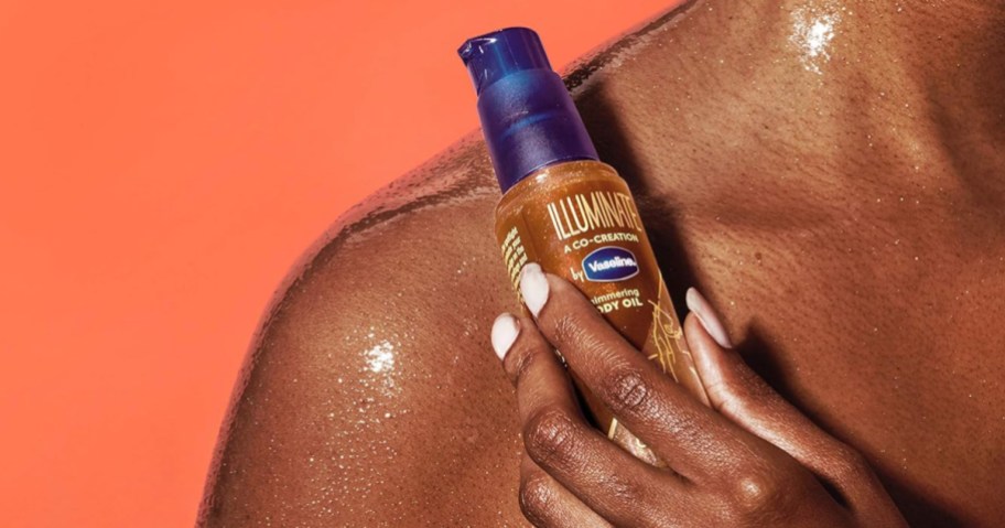Hand holding bottle of Vaseline shimmer oil