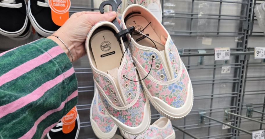 Hand holding a pair of girl's Wonder Nation slip on shoes