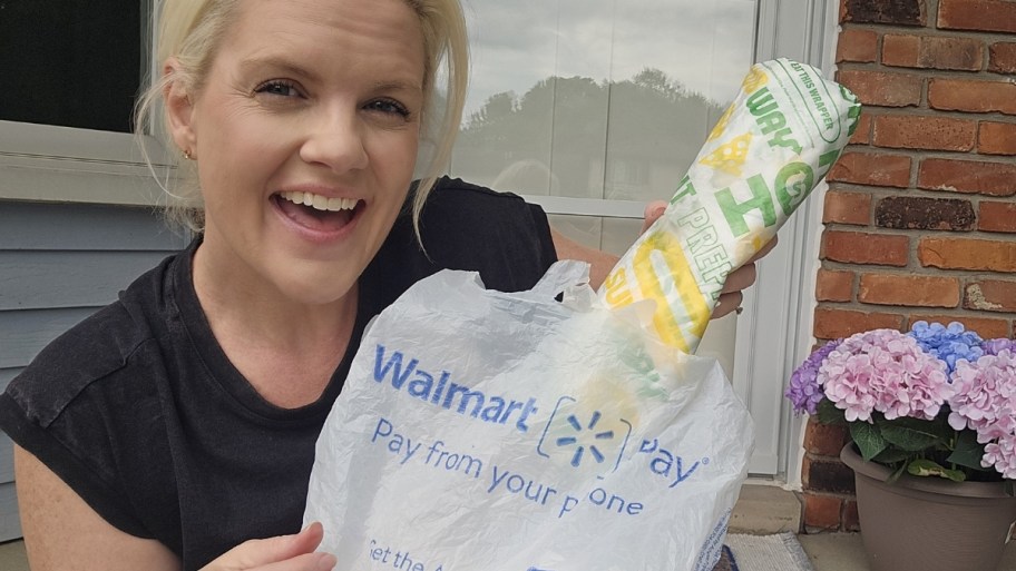 a woman pulling a subway sandwich out of a plastic walmart bag