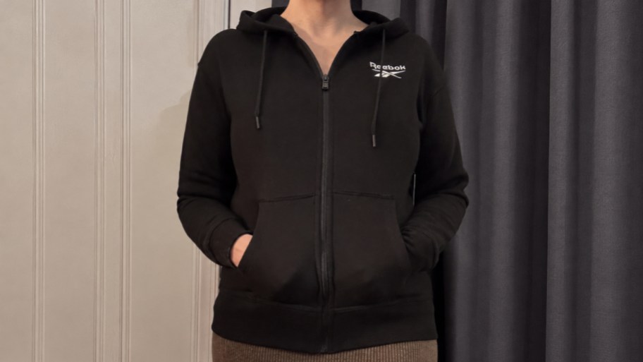 a woman wearing a black reebok hoodie