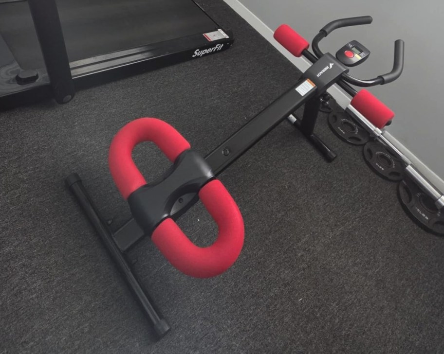a black and red ab machine set up in a workout room