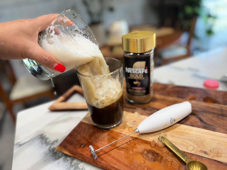 adding frothed milk to a latte
