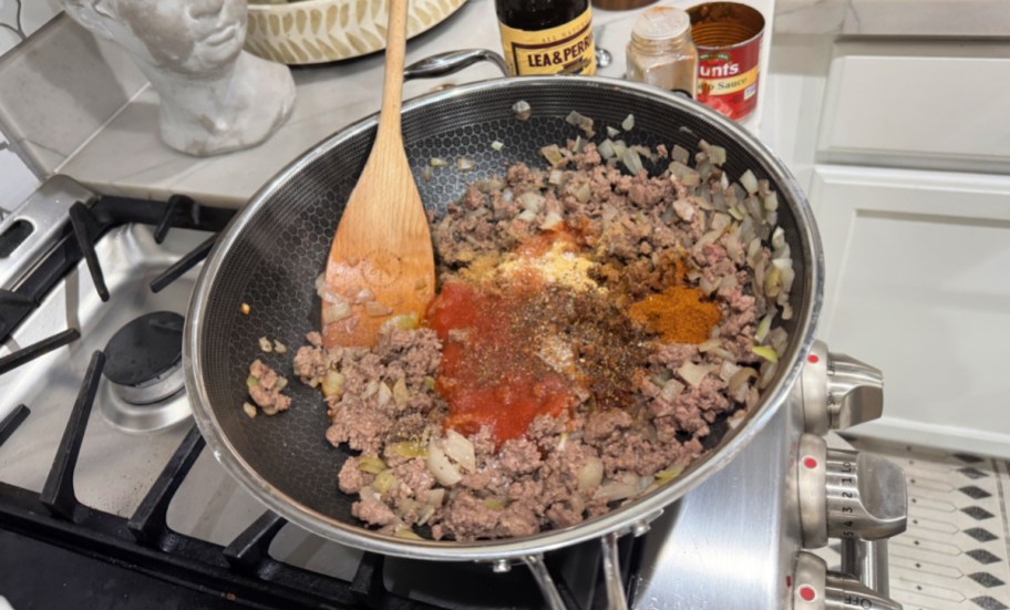 adding tomato sauce and seasonings to a skillet