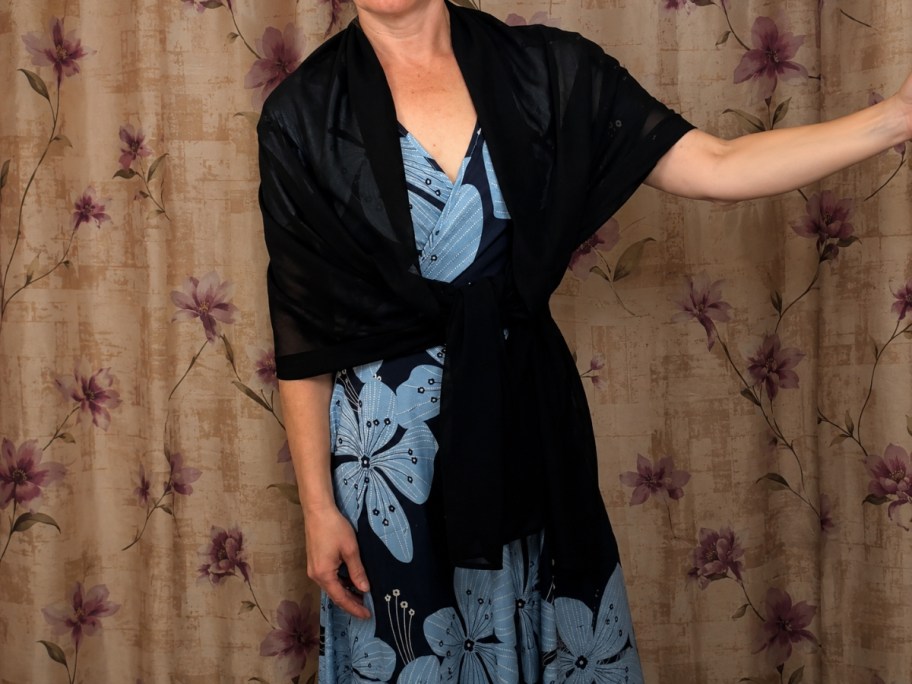 a woman wearing a black shawl with a blue and black floral dress