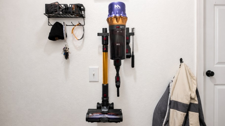 a cordless vacuum hanging on a wall charging