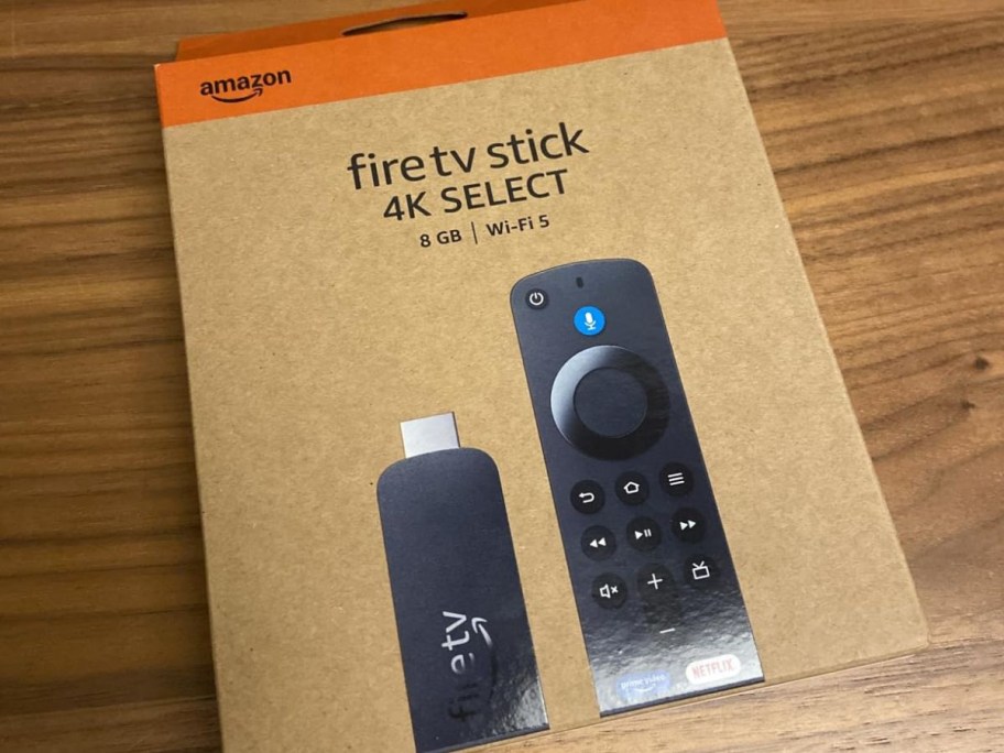 A cardboard box for an Amazon Fire TV Stick 4K Select on a wooden surface.
