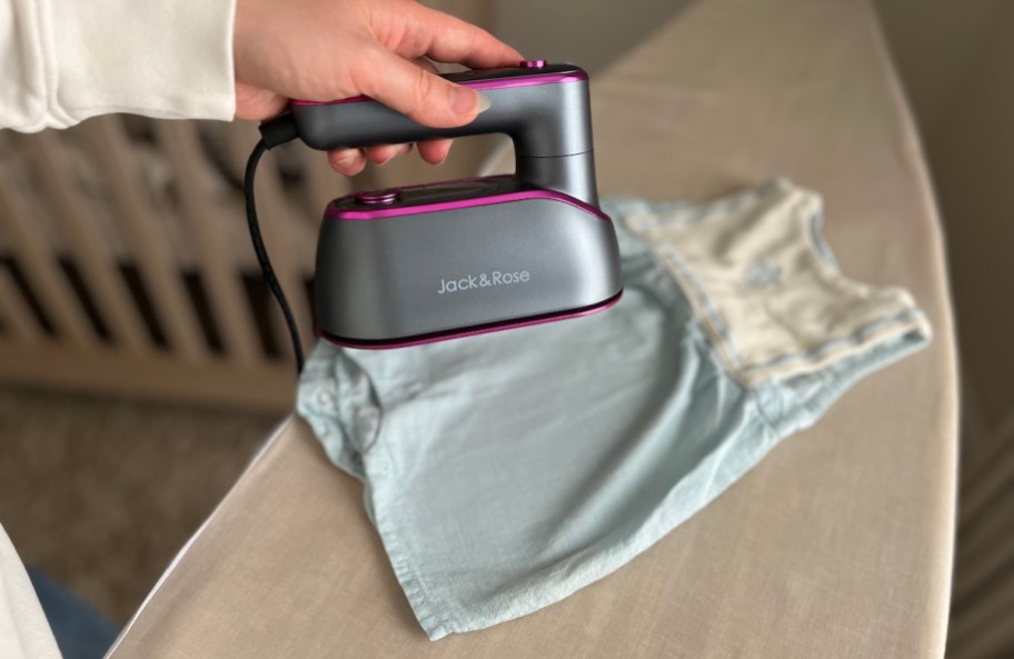 hand holding Jack and Rose portable steamer over baby outfit