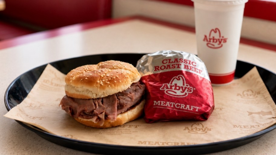 Two Arbys sandwiches on a tray with a fountain drink