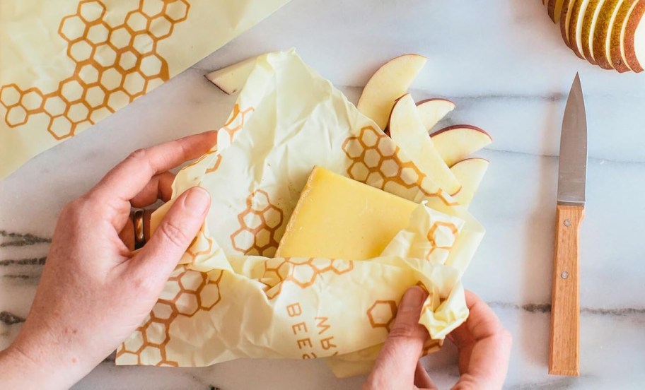 hand unwrapping block of cheese from bees wrap 