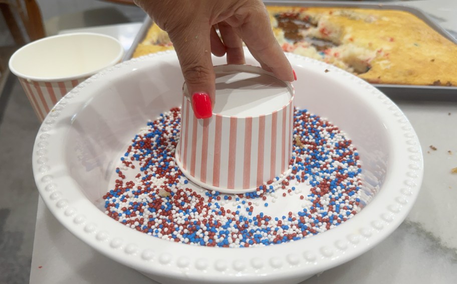 hand putting cake cup down in sprinkles