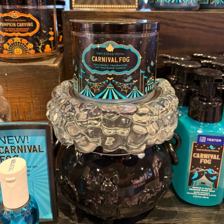 a 3 wich candle on top of a cauldron pedestal on display in a store