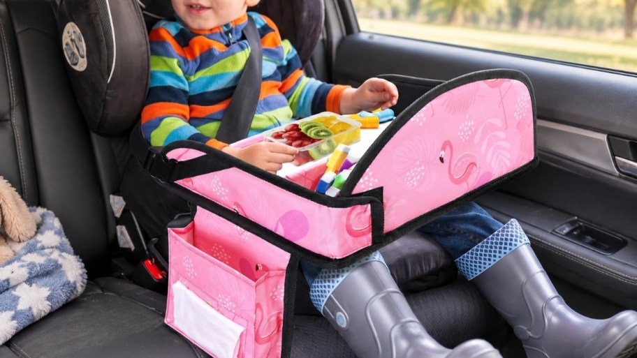 little boy in a carseat with a travel tray in his lap