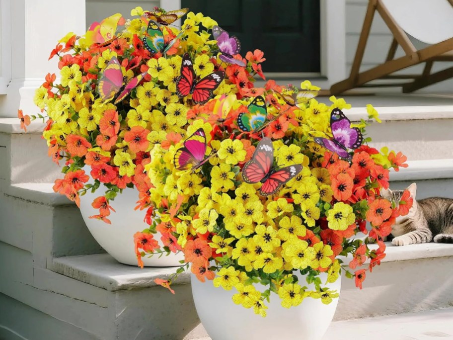 yellow and orange flowers in white pots on stairs