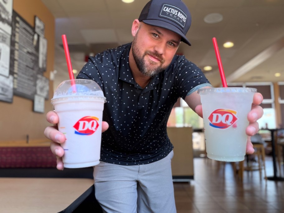 A man holding two beverages in a Dairy Queen restaurant, one in each hand.