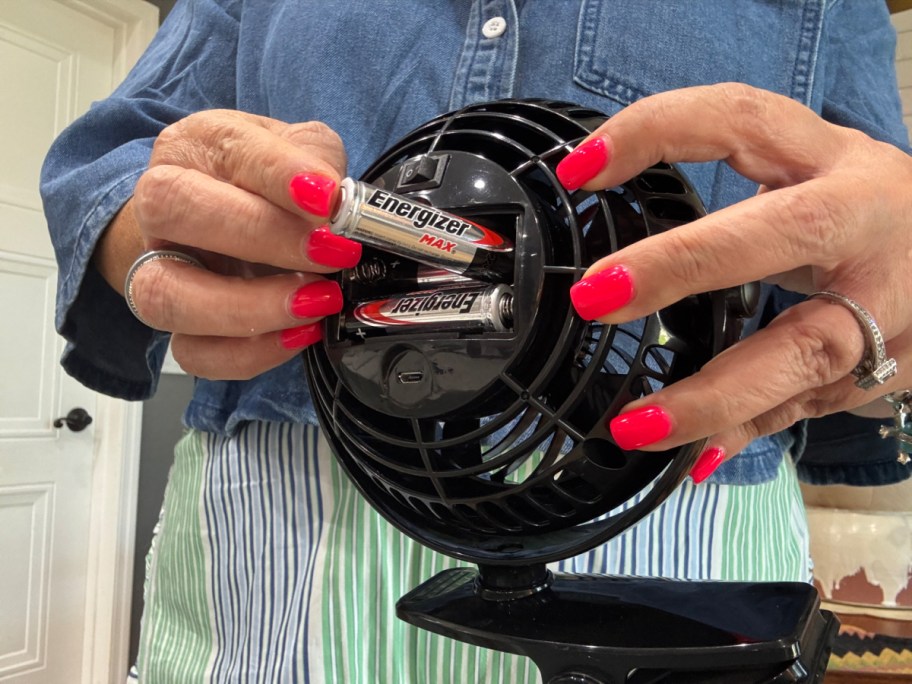 woman inserting batteries into a portable fan