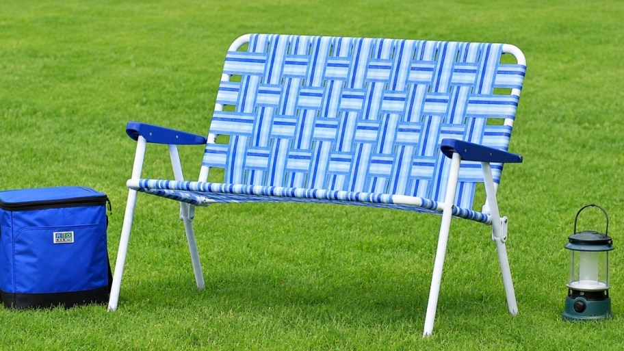 a folding loveseat sized lawn chair sitting in the grass