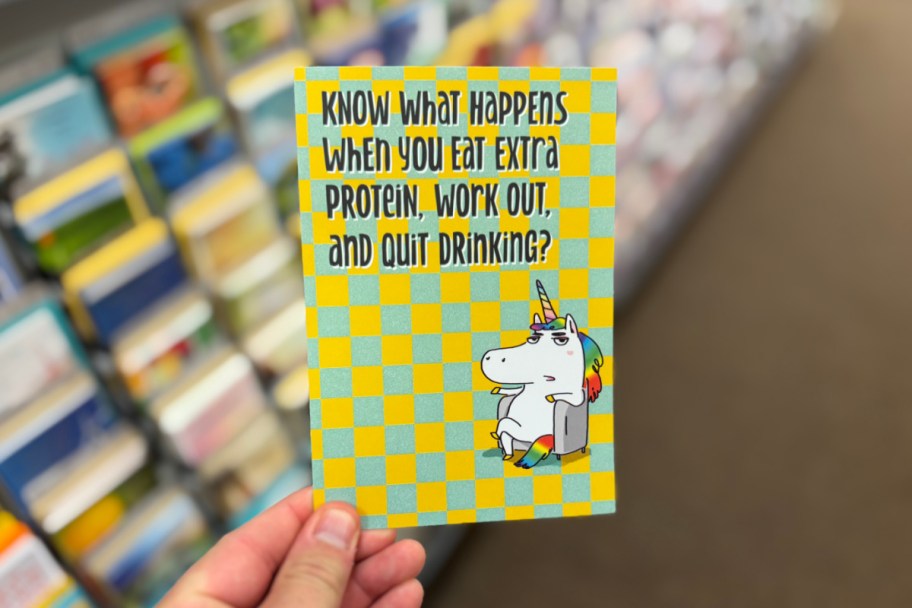 hand holding funny unicorn card in store