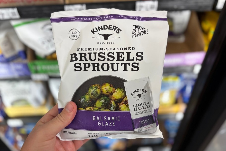 mans hand holding a bag of frozen brussells sprouts