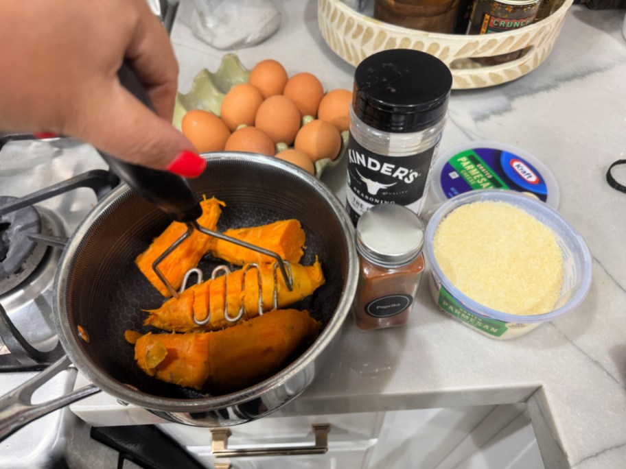 mashing sweet potatoes in a pot