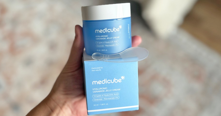 hand holding blue medicube moisturizer jar and box