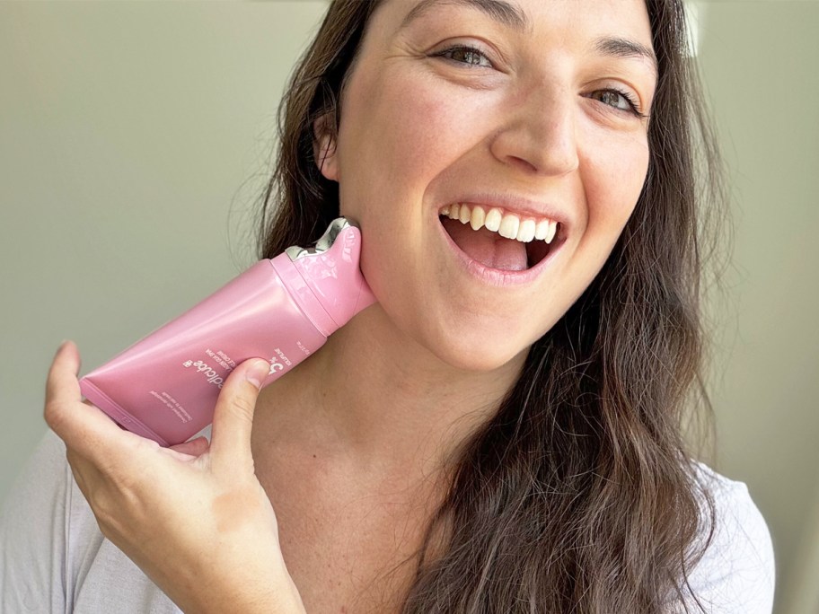 woman applying pink gua sha nack cream